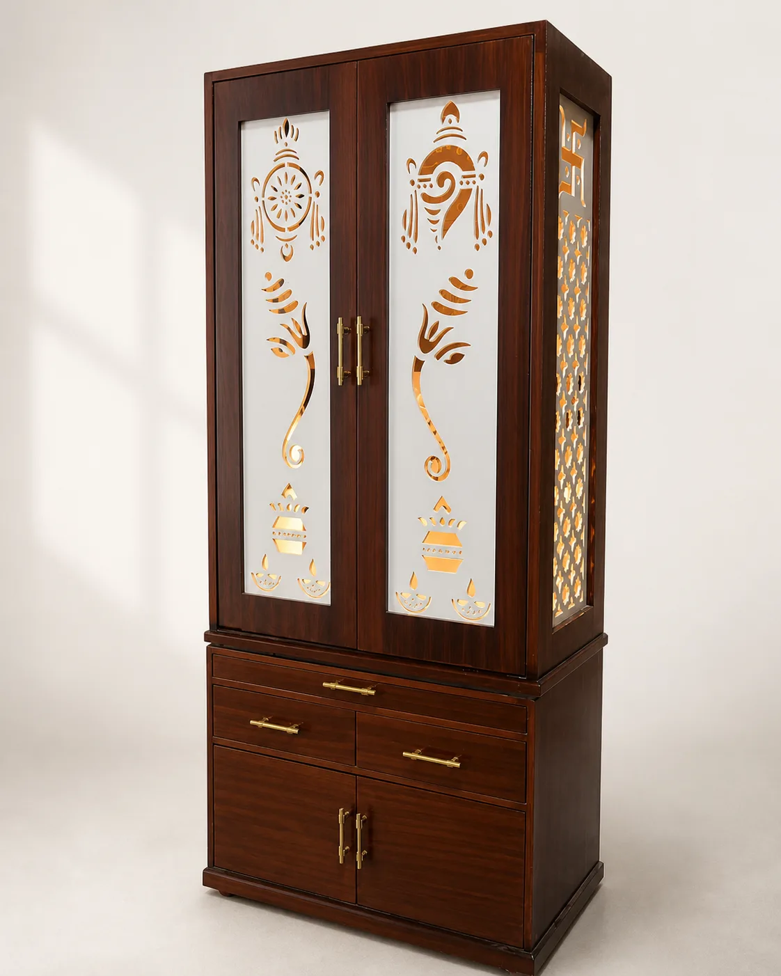 Walnut cabinet mandir with two tall doors carrying gold Ganesh and kalash motifs.
