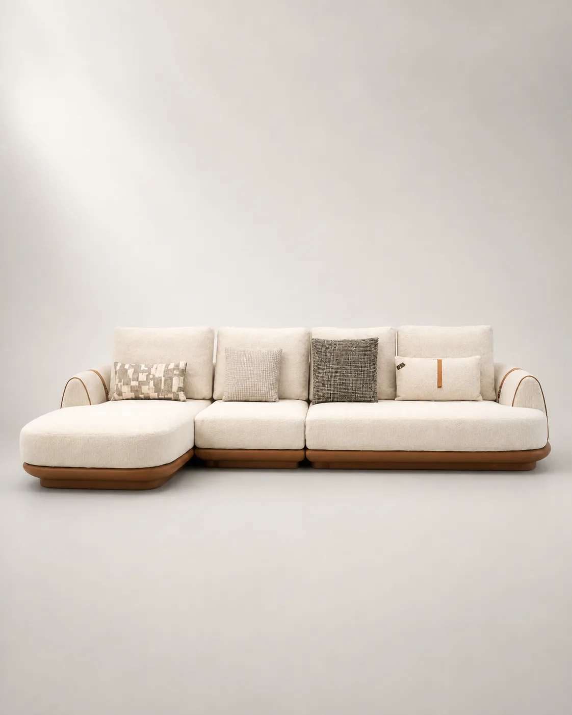 Cream boucle L-shaped sofa with tan leather trim and arm strap detail.
