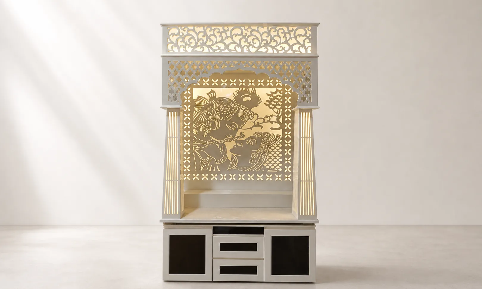 Mandir unit with square backlit Radha-Krishna jaali panel, reeded pillars and fretwork crown.